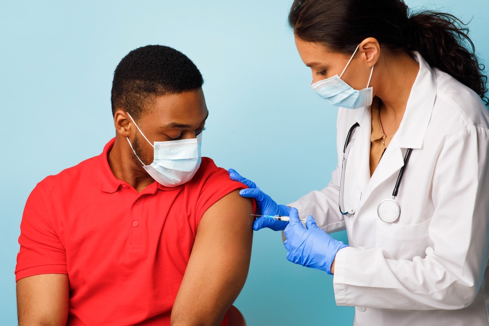 Médica aplicando vacina no braço de paciente
