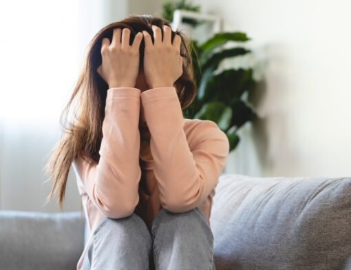 Pessoa sentada com as mãos no rosto em momento de crise.