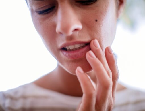 Uma pessoa com a mão no canta na boca, sensação de incômodo causado pelo vírus do herpes tipo1.