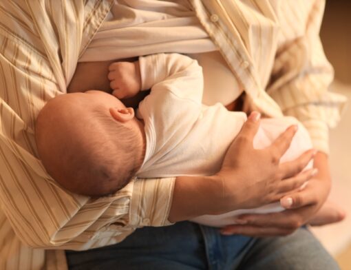 Um bebê sendo amamentado pela sua mãe com leite materno.