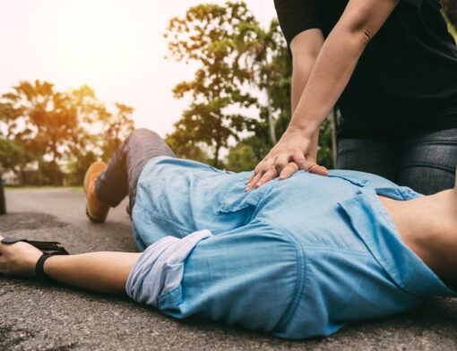 Pessoa deitada no chão recebendo massagem cardíaca por uma pessoa preparada com as técnica correta de reanimação em casos de infarto