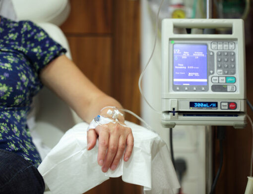 Paciente sentado em uma poltrona durante uma sessão de quimioterapia em um ambiente hospitalar.