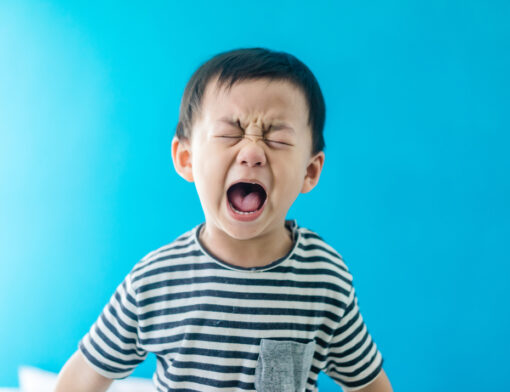 Criança demonstrando insatisfação, com semblante de choro e expressão facial de gritos.