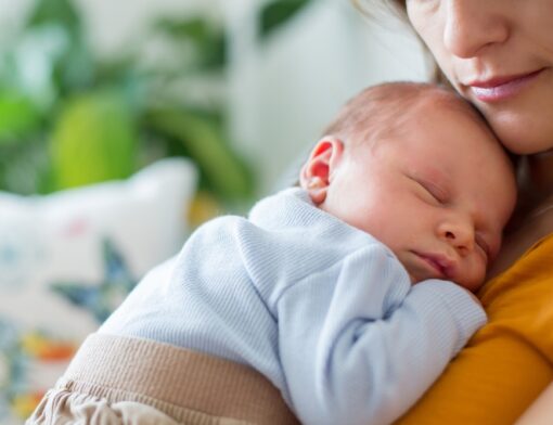 Mãe com um bebê (RN) recém nascido no colo.