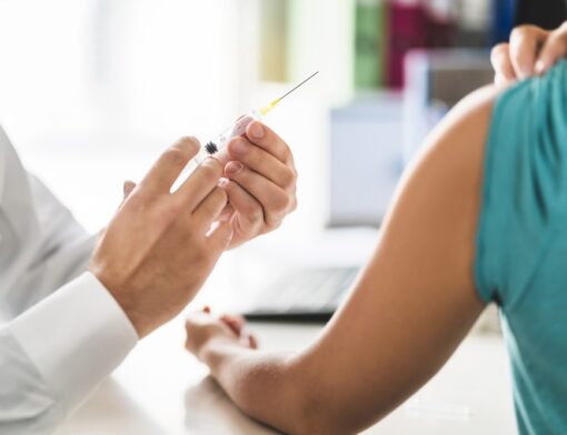 rofissional de Saúde preparando uma seringa para aplicar a vacina contra HPV em uma pessoa. 