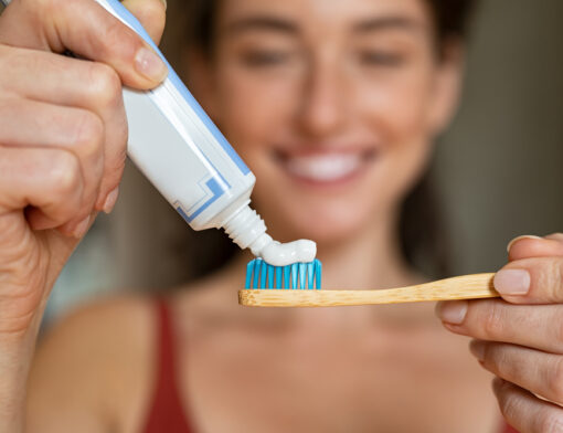 Pessoa aplicando o creme dental em uma escova de dentes.