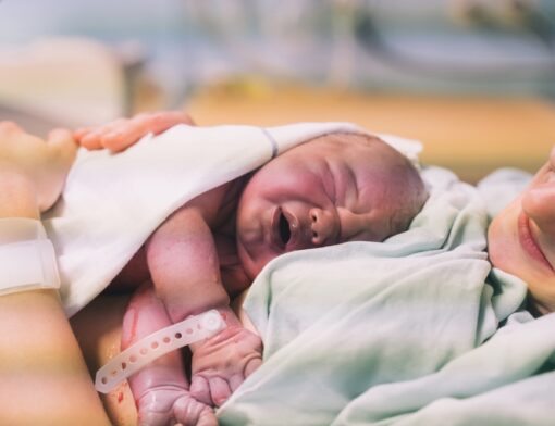 Mãe com o bebê (RN) recém-nascido no colo logo após o nascimento.