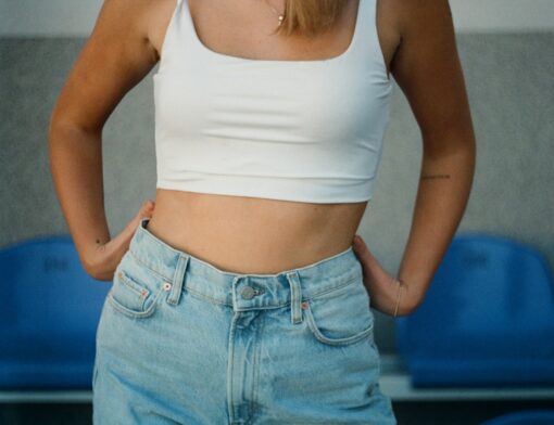 Pessoa de corpo magro vestida com uma calça jeans e uma regata branca