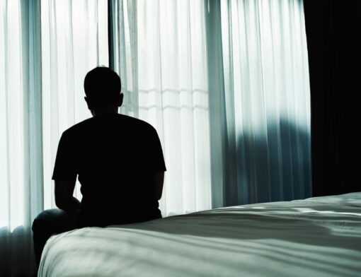 Pessoa sentada na cama devido a falta de sono