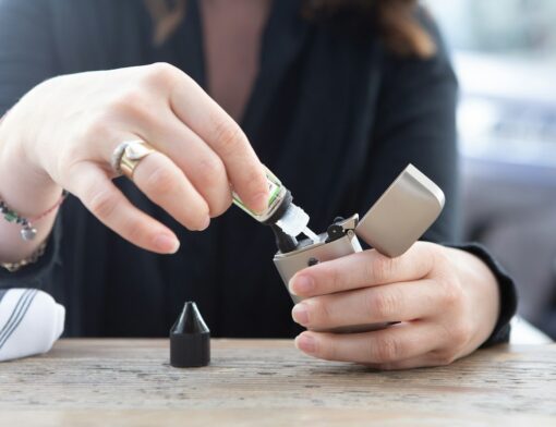 Pessoa preparando um vape (cigarro eletrônico) para consumir.