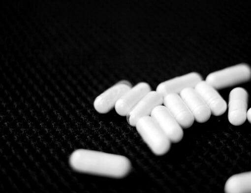 Cápsulas de medicamento antidepressivo espalhadas em uma superfície escura.