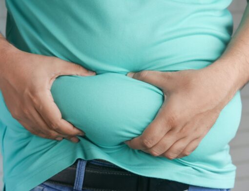 Pessoa excesso de peso segurando a barriga exibindo gordura localizada