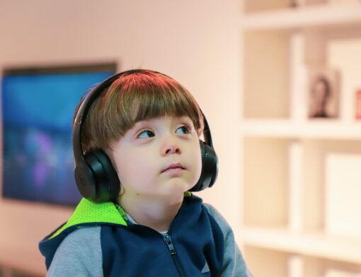 Criança neuroatípica utilizando um protetor auricular (fones de ouvidos) demonstrando calma e foco.