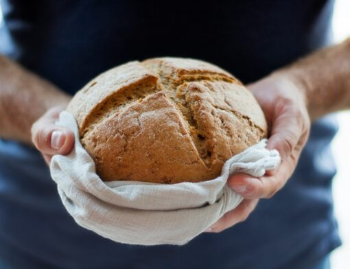 Pessoa segurando um pão assado com as duas mãos