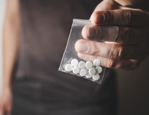 Pessoa com um envelope plástico transparente contendo pílulas de tramadol