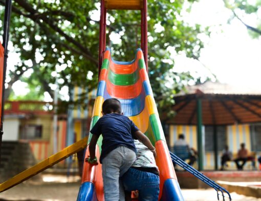 Duas crianças brincando em um escorregador em uma área de recreação infantil.