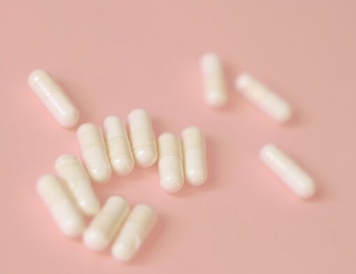 Cápsulas de medicamentos sobre uma superfície com tom salmão