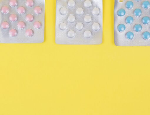 A imagem apresenta três cartelas de comprimidos dispostas em uma superfície amarela. Cada cartela contém comprimidos de cores diferentes. Uma forma ilustrada de diferenciar ibuprofeno e cetoprofeno.