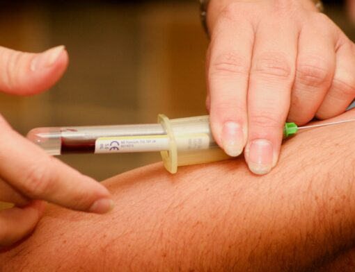 Profissional da saúde coletando exame de sangue no braço de uma pessoa